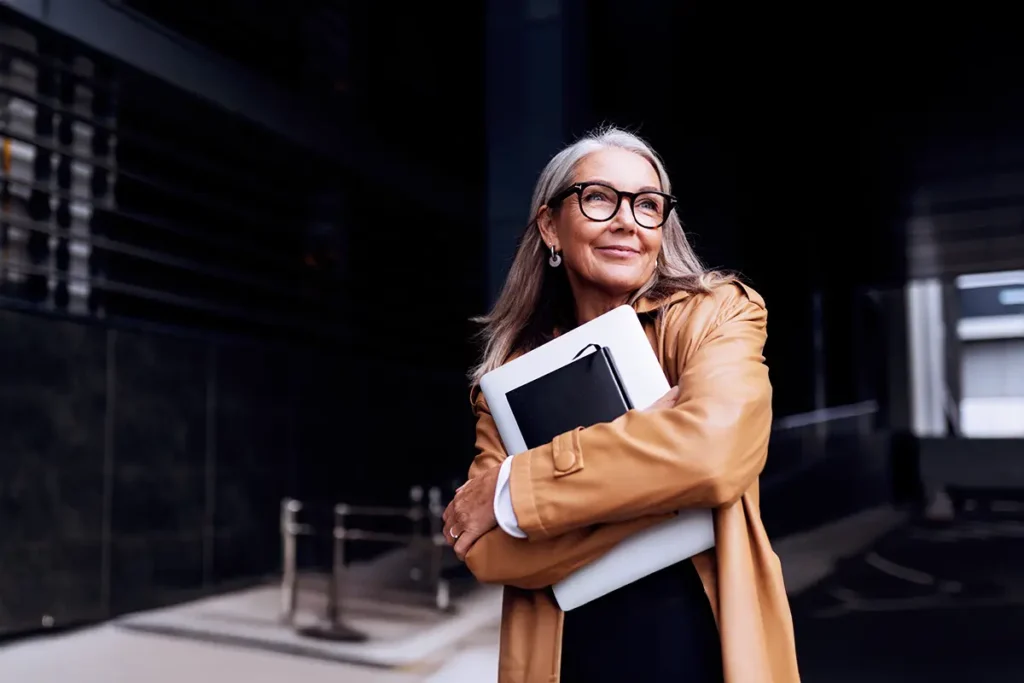 Woman Smiling While Using Laptop Outdoors.webp